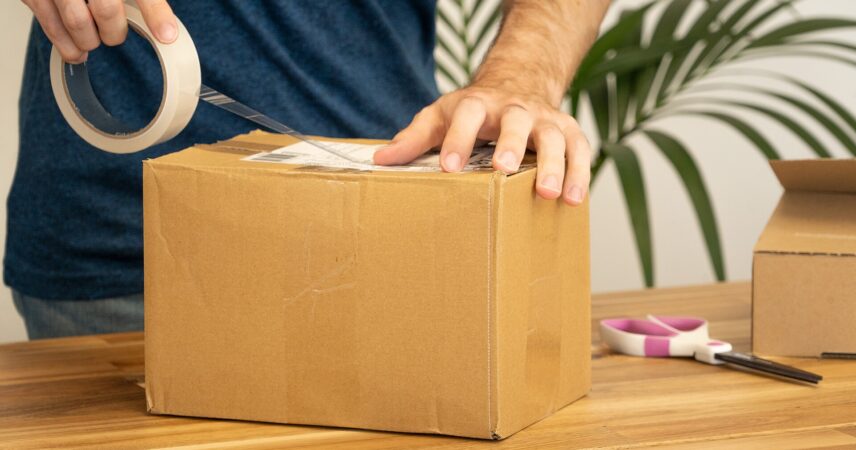 Persona sellando y etiquetando un paquete para envío